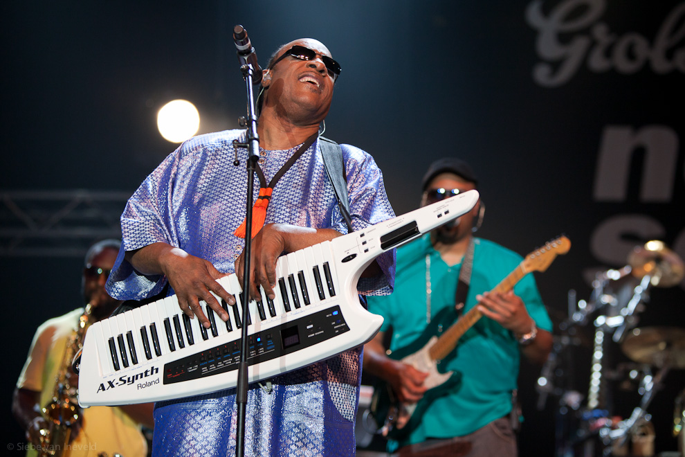 Stevie Wonder playing on shoulder synthesizer.